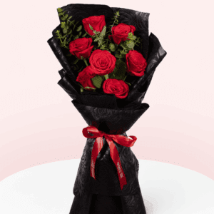 Red roses and eucalyptus bouquet wrapped in black floral paper