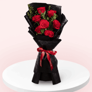 Red roses and eucalyptus bouquet wrapped in black floral paper