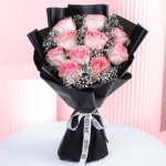 A romantic bouquet of pink roses wrapped in a black wrap.