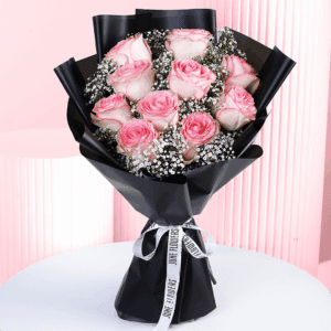 A romantic bouquet of pink roses wrapped in a black wrap.