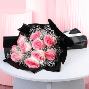A romantic bouquet of pink roses wrapped in a black wrap.
