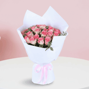 A bouquet featuring blush pink roses with green fillers in an elegant white wrap, finished with a soft pink ribbon.