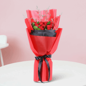 A bouquet of red roses with green fillers in a red and black wrap, finished with a black ribbon.