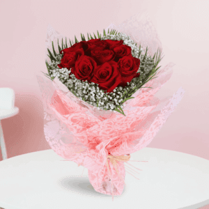 A bouquet featuring red roses with white baby’s breath in a pink Valentine wrap, finished with a “Love You” message topper.