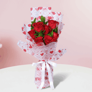 Red roses bouquet with green fillers in a heart-print wrap, finished with a white ribbon.
