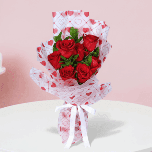 Red roses bouquet with green fillers in a heart-print wrap, finished with a white ribbon.